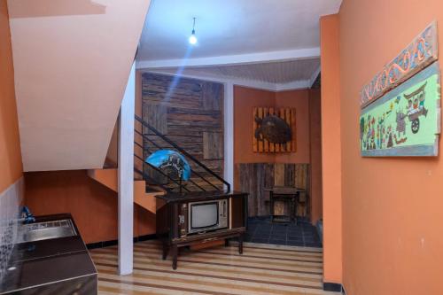 a living room with a tv and a staircase at RedDoorz Syariah near Akmil Magelang in Magelang