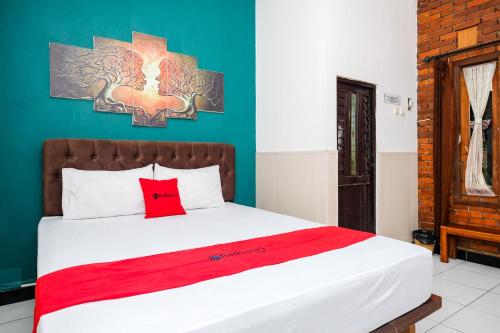 a bedroom with a large bed with a red pillow at RedDoorz Syariah near Akmil Magelang in Magelang