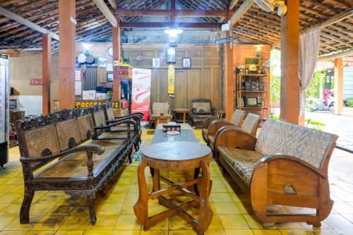 a room filled with wooden benches and a table at RedDoorz Syariah near Akmil Magelang in Magelang