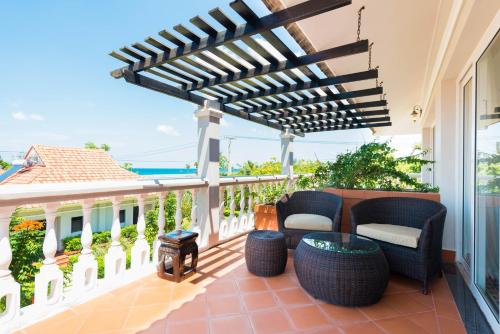 a patio with wicker chairs and a wooden pergola at Mercury Phu Quoc Resort & Villas in Phu Quoc