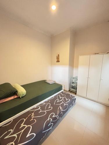 una camera da letto con un letto con una coperta verde e armadi di SYARIAH - Beautiful 3BR Home - 8 min from Centre by Sakura a Krawang