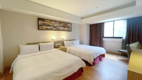 a hotel room with two beds and a window at Delton Hotel in Kaohsiung