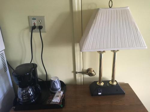 a table with a lamp and a coffee maker on it at Norwalk Inn in Norwalk