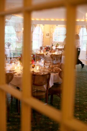 a dining room with white tables and chairs with people walking around at Franconia Inn in Franconia