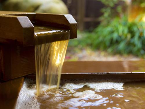 a stream of water coming out of a wooden fountain at Hashinoya Bekkan Ransui in Kobe
