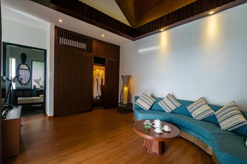a living room with a blue couch and a table at Mercury Phu Quoc Resort & Villas in Phu Quoc