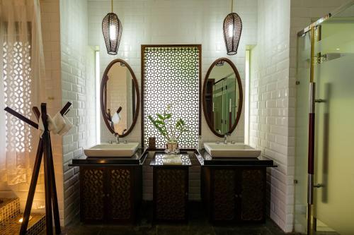 a bathroom with two sinks and two mirrors at Mercury Phu Quoc Resort & Villas in Phu Quoc