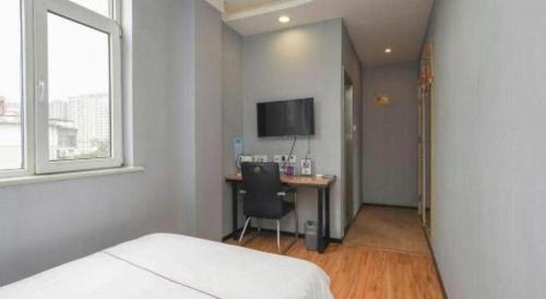 a bedroom with a bed and a desk with a television at PAI Hotels Shijiazhuang Railway Station West Square in Shijiazhuang