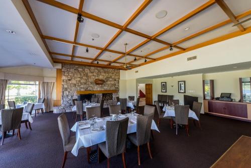 a dining room with tables and chairs and a fireplace at VR Rotorua Lake Resort in Rotorua