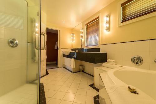 a bathroom with a tub and a shower and a sink at VR Rotorua Lake Resort in Rotorua