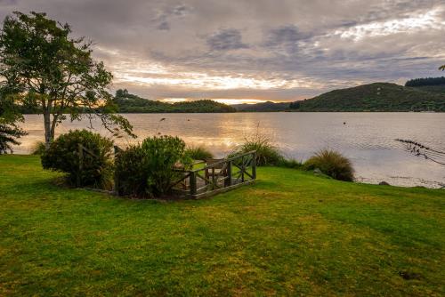 a bench sitting on the grass near a body of water at VR Rotorua Lake Resort in Rotorua