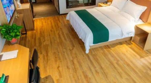a bedroom with a bed and a wooden floor at GreenTree Inn Express Datong High-Speed Railway Station Wanda Plaza Fangte in Datong