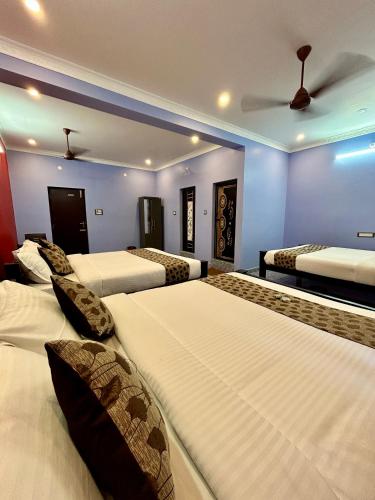 a hotel room with three beds and a ceiling at Le Oasis Auro'Raa in Puducherry
