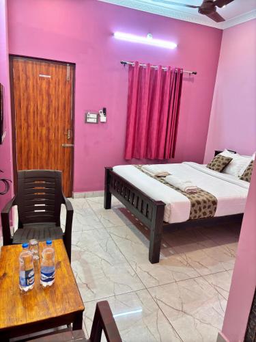 a pink room with a bed and a table and chairs at Le Oasis Auro'Raa in Puducherry