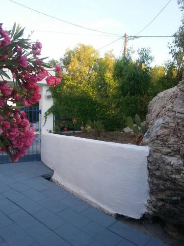 a white wall with a garden with pink flowers at Iris Studios in Archangelos
