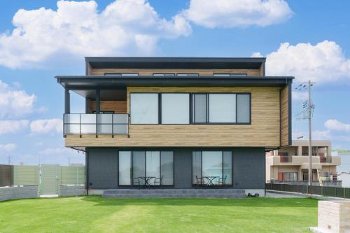 a modern house with a green lawn in front of it at One's You Villa Awaji in Awaji