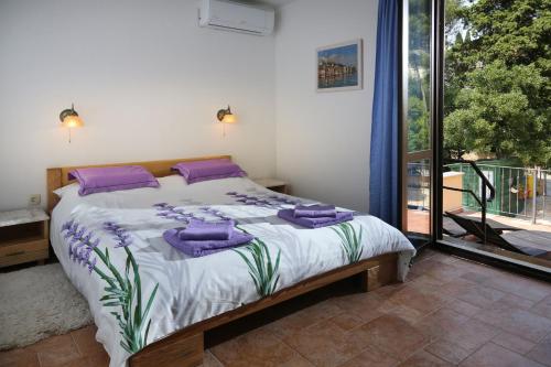 a bedroom with a bed with purple pillows and a window at Rooms Figarola in Rovinj