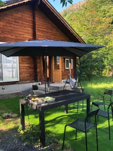 a picnic table with an umbrella in front of a house at 里山辺ウッドハウスちいさいおうち in Matsumoto