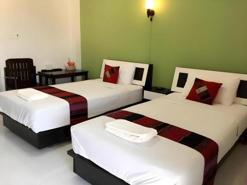 two beds in a hotel room with a table at Nan Treasure Hotel in Nan
