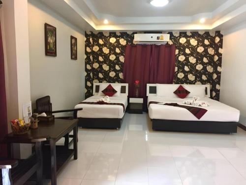 a hotel room with two beds and a table and a table sidx sidx at Nan Treasure Hotel in Nan