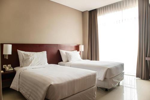 a hotel room with two beds and a window at Karlita Hotel Tegal in Tegal