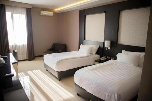 a hotel room with two beds and a window at Karlita Hotel Tegal in Tegal