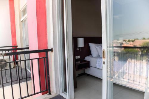 a door to a balcony with a bed in a room at Karlita Hotel Tegal in Tegal