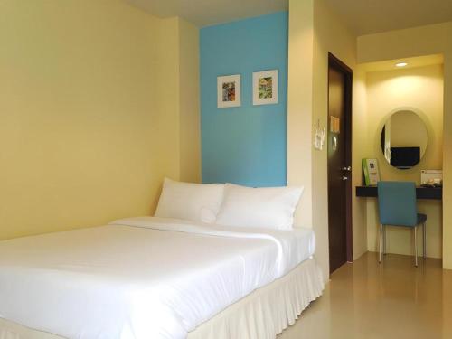 a bedroom with a white bed and a blue wall at C2 Residence Hotel in Lampang