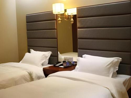 two beds in a hotel room with a mirror at Milu Hotel in Guangzhou