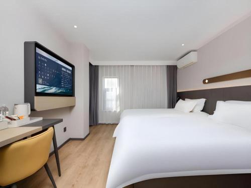 a hotel room with a bed and a desk and a tv at Jinjiang Inn Shenzhen Airport in Shenzhen