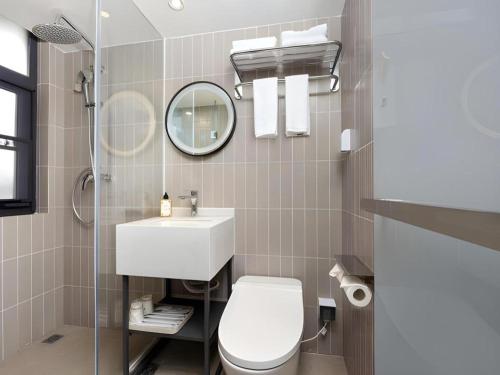 a bathroom with a toilet and a sink and a mirror at Jinjiang Inn Shenzhen Airport in Shenzhen