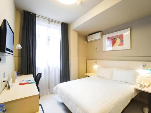 a hotel room with a bed and a desk and a window at Jinjiang Inn Shenzhen Airport in Shenzhen