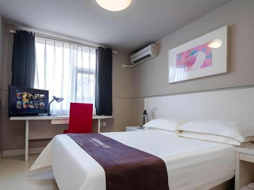 a bedroom with a bed and a desk and a red chair at Jinjiang Inn Shenzhen Airport in Shenzhen