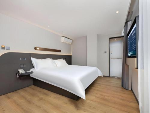 a bedroom with a large white bed and a tv at Jinjiang Inn Shenzhen Airport in Shenzhen