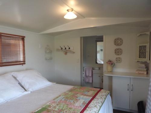 a small bedroom with a bed and a kitchen at Long Bay Motor Camp in Coromandel Town