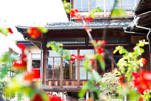 a house with windows and red flowers in front of it at Yamada Bessou くつろぎの温泉宿 山田別荘 in Beppu