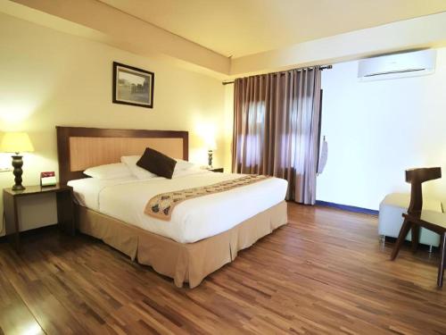 a hotel room with a bed and a large window at Sambi Resort, Spa & Resto in Yogyakarta