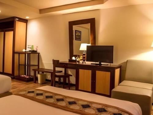 a living room with a television and a desk with a couch at Sambi Resort, Spa & Resto in Yogyakarta