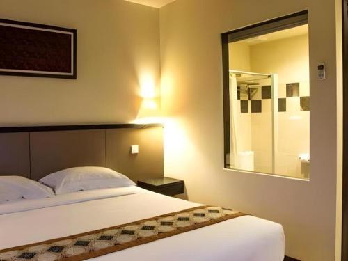 a bedroom with a large bed and a mirror at Sambi Resort, Spa & Resto in Yogyakarta