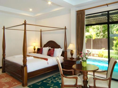 a bedroom with a canopy bed and a table and chairs at Nattha Waree Hot Spring Resort and Spa in Ao Nang Beach