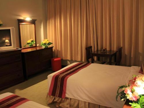 a hotel room with a bed and a table and a television at Thepnakorn Hotel in Buriram