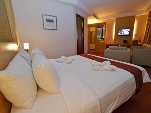 a hotel room with a large white bed with pillows at The Axana Hotel in Padang