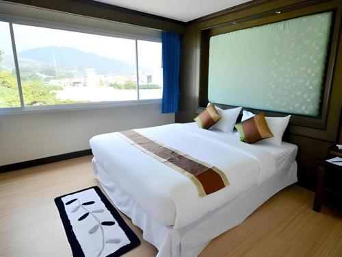 a bedroom with a large bed with a large window at Piyaporn Pavilion Hotel in Mae Sai