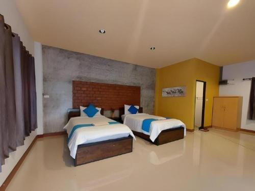 two beds in a large room with yellow walls at Ban Naam Resort in Mae Sai