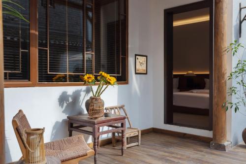 a room with a table and chairs and a vase with flowers at 凤凰古城树喜民宿店Shuxi Guesthouse- Fenghuang Ancient Town in Fenghuang