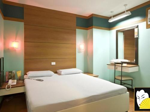 a bedroom with a bed and a desk and a mirror at Hotel Sogo Tarlac in Tarlac