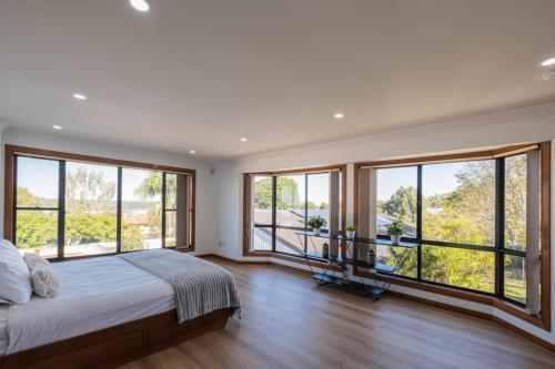 a bedroom with a bed and large windows at 6bed Macgregor Home in Brisbane