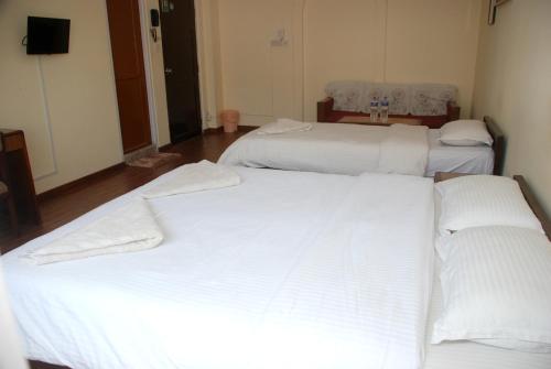 two beds in a hotel room with white sheets at Kathmandu Madhuban Guest House in Kathmandu