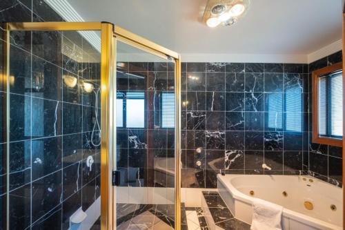 a bathroom with a tub and a glass shower at 6bed Macgregor Home in Brisbane