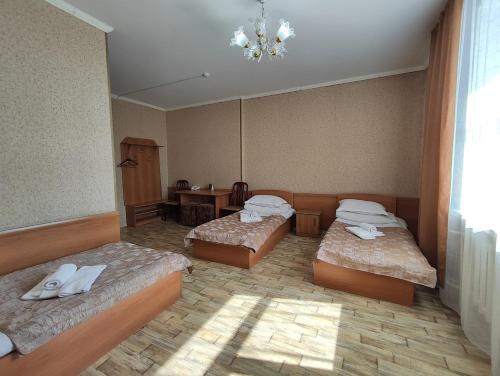 a room with three beds and a chandelier at Гостиница Караганда in Karagandy